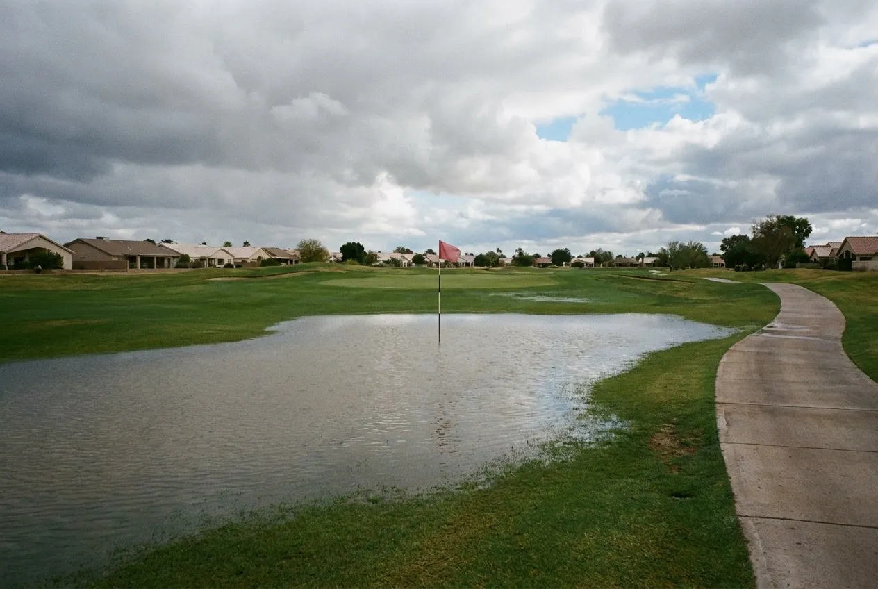 Stormwater stands in a broad shallow sheet across a Sun City West golf fairway after a heavy rain.