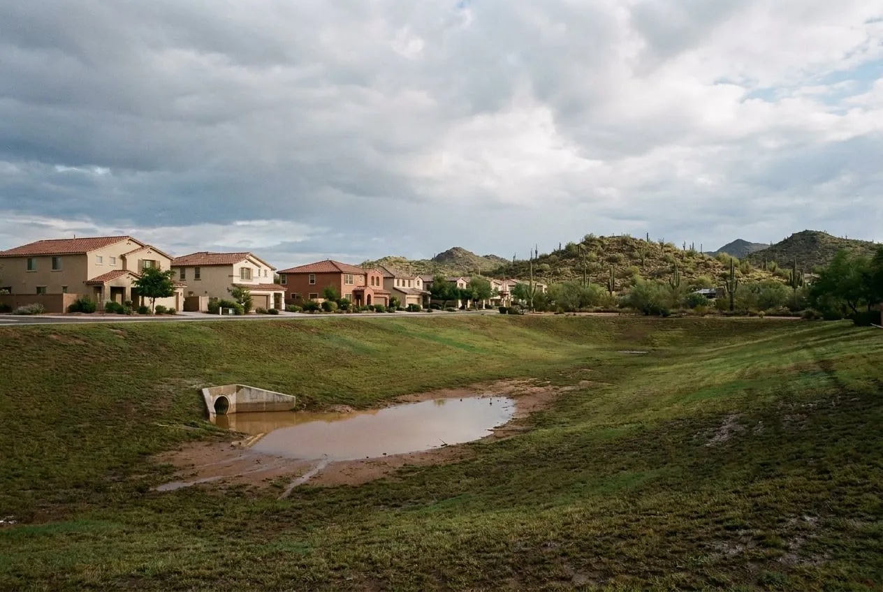 Storm water sits in the low end of a grassy neighborhood retention basin in north Phoenix the morning after a monsoon storm.
